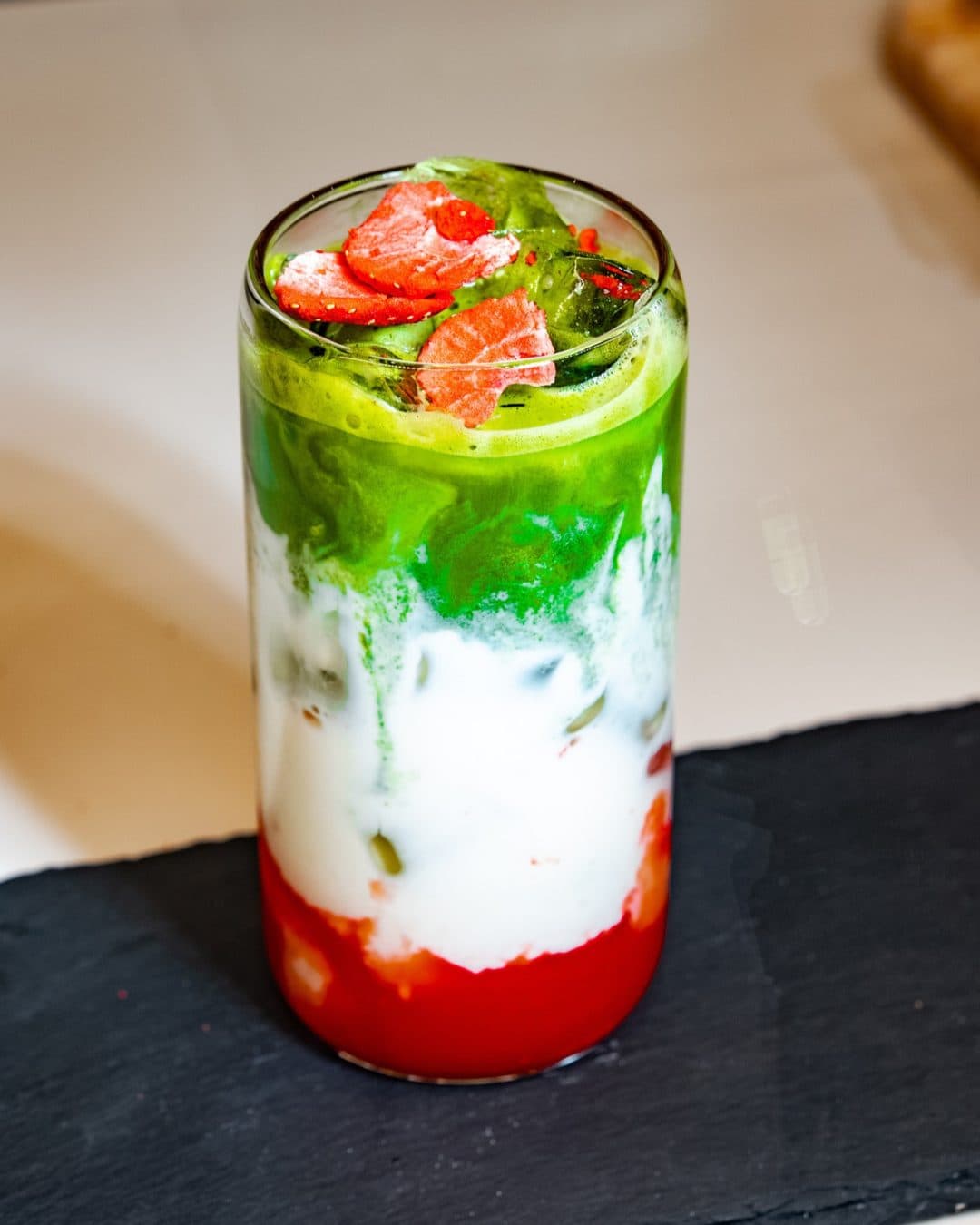 Ein geschichteter Matcha mit Erdbeeren im hohen Glas